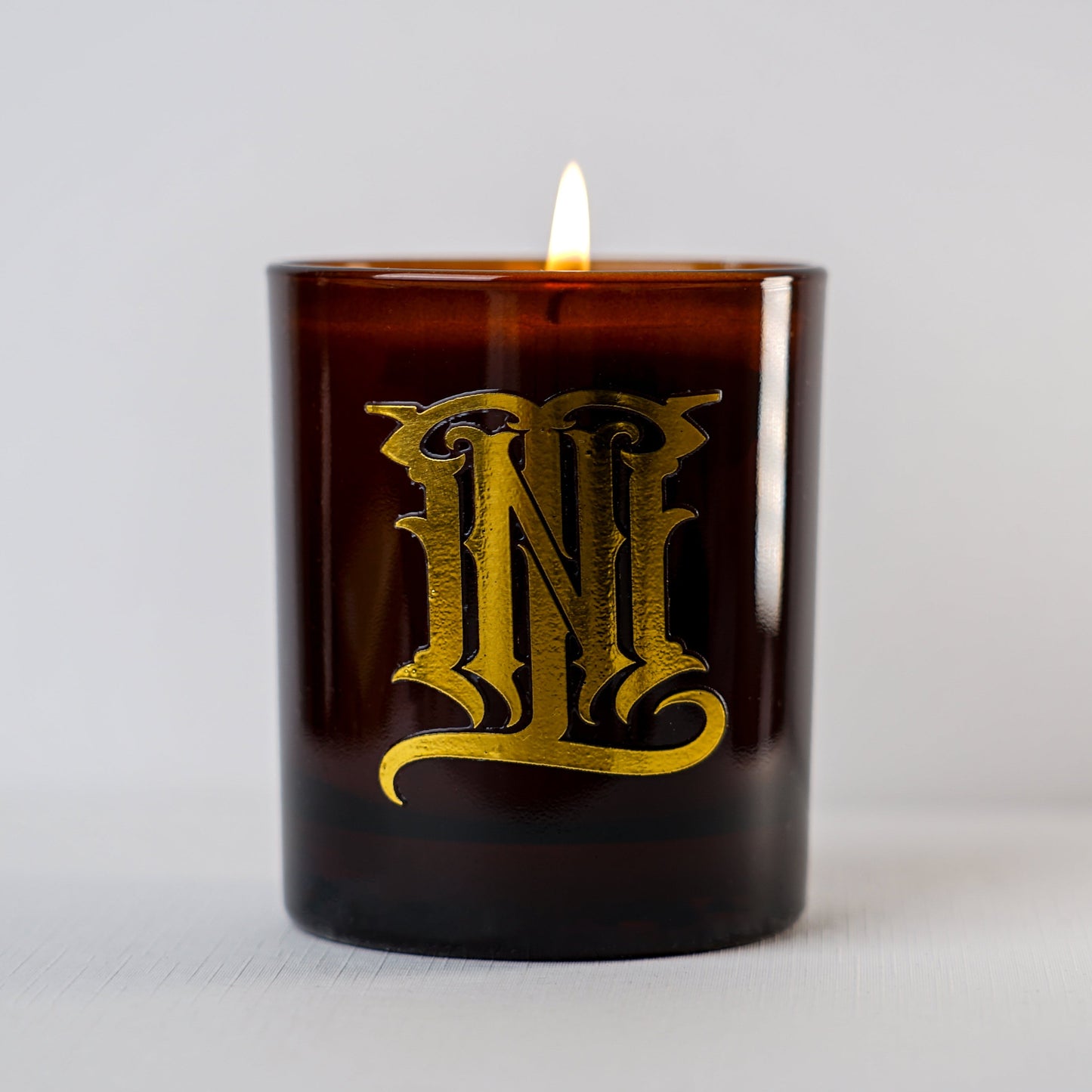 Brown candle with gold lettering on a light gray background