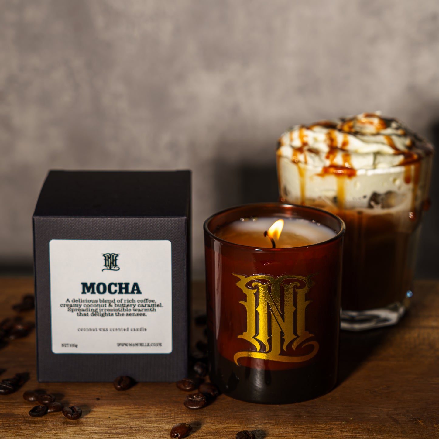 Mocha-scented candle with packaging and a cup of mocha in the background on a wooden surface.