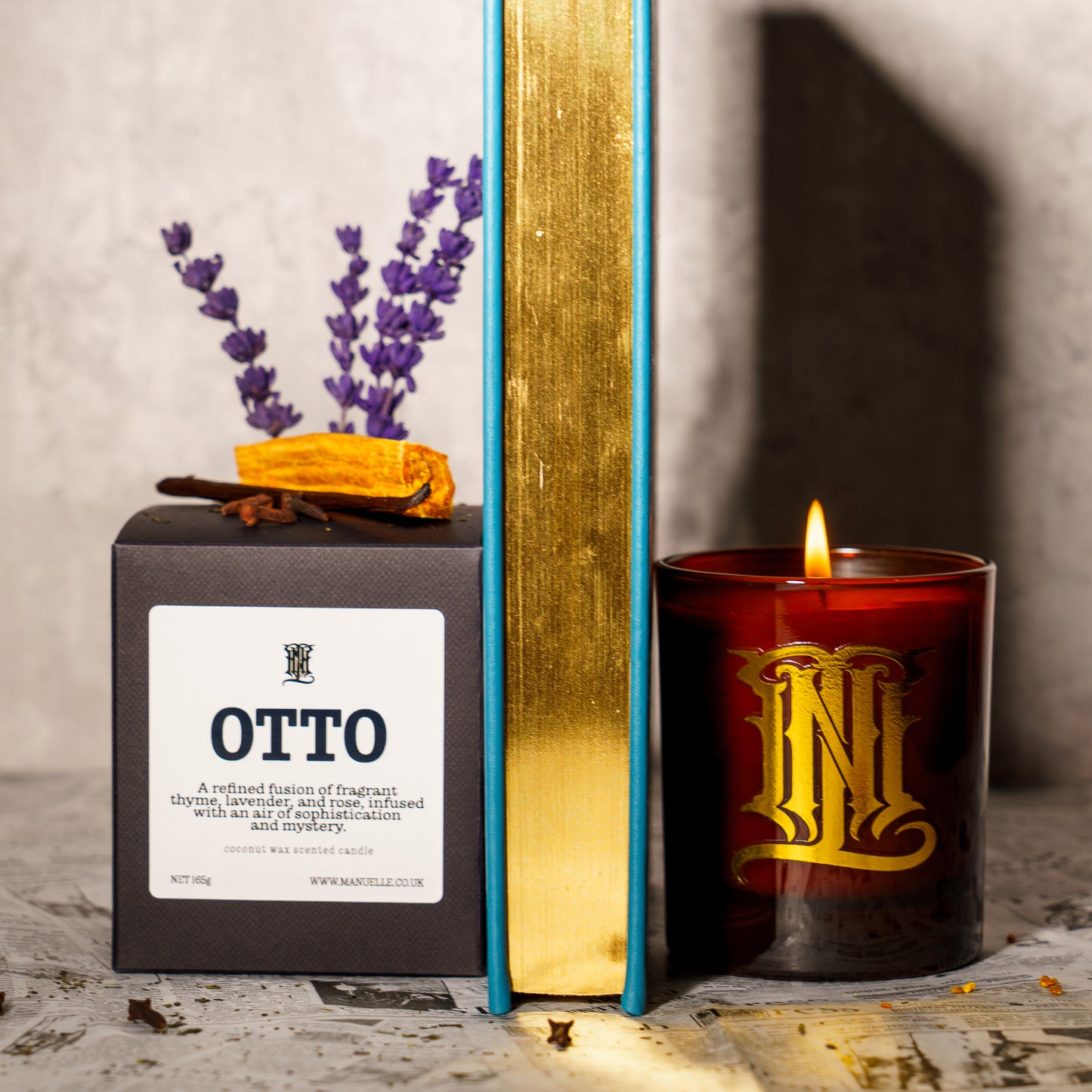 Candle with 'OTTO' branding next to its packaging on a textured surface.
