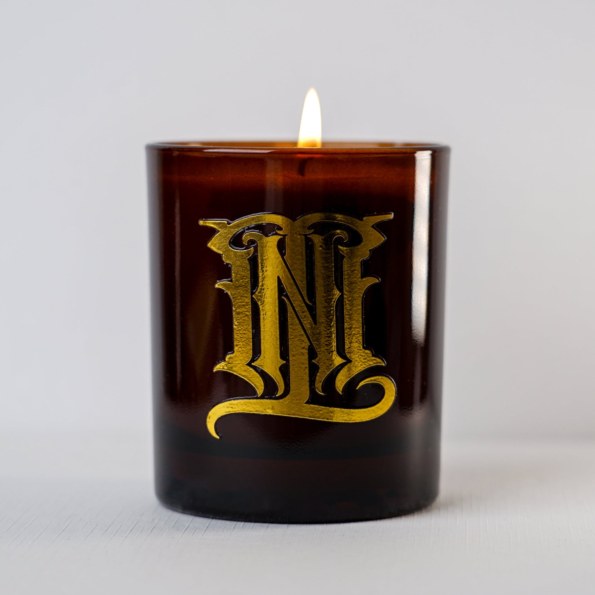 Brown candle with gold lettering on a light gray background