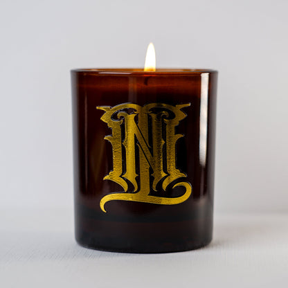 Brown candle with gold lettering on a light gray background
