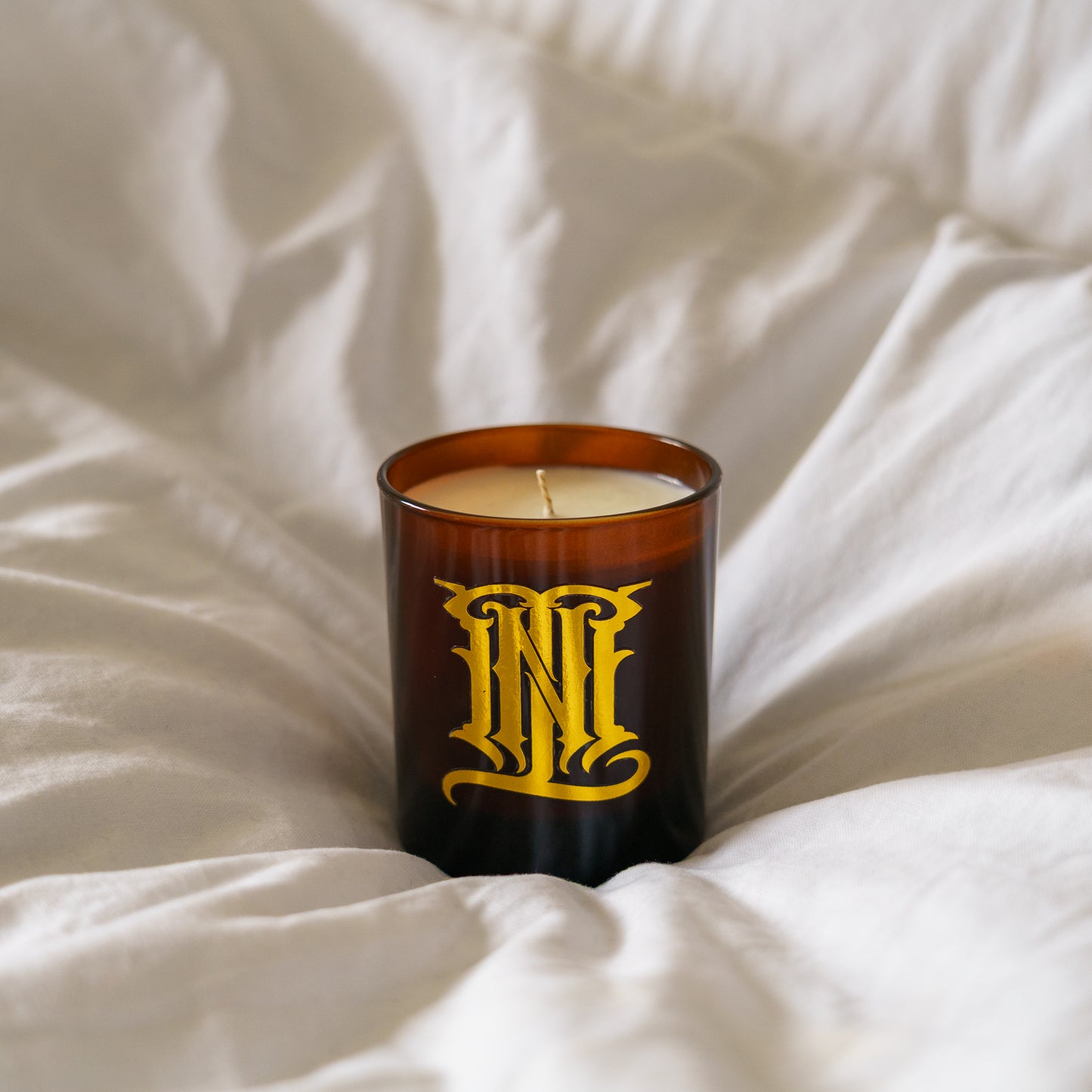 Candle with a decorative label on a white fabric background