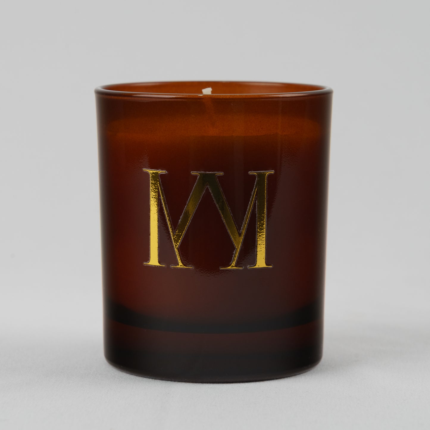 Brown candle with a gold letter 'M' on a white background