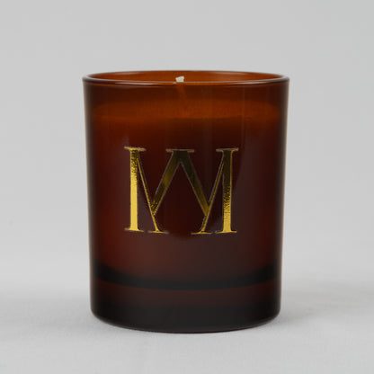 Brown candle with a gold letter 'M' on a white background