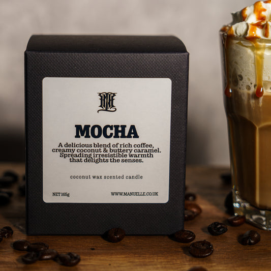 Manuelle Mocha candle packaging with a glass of coffee mocha in the background