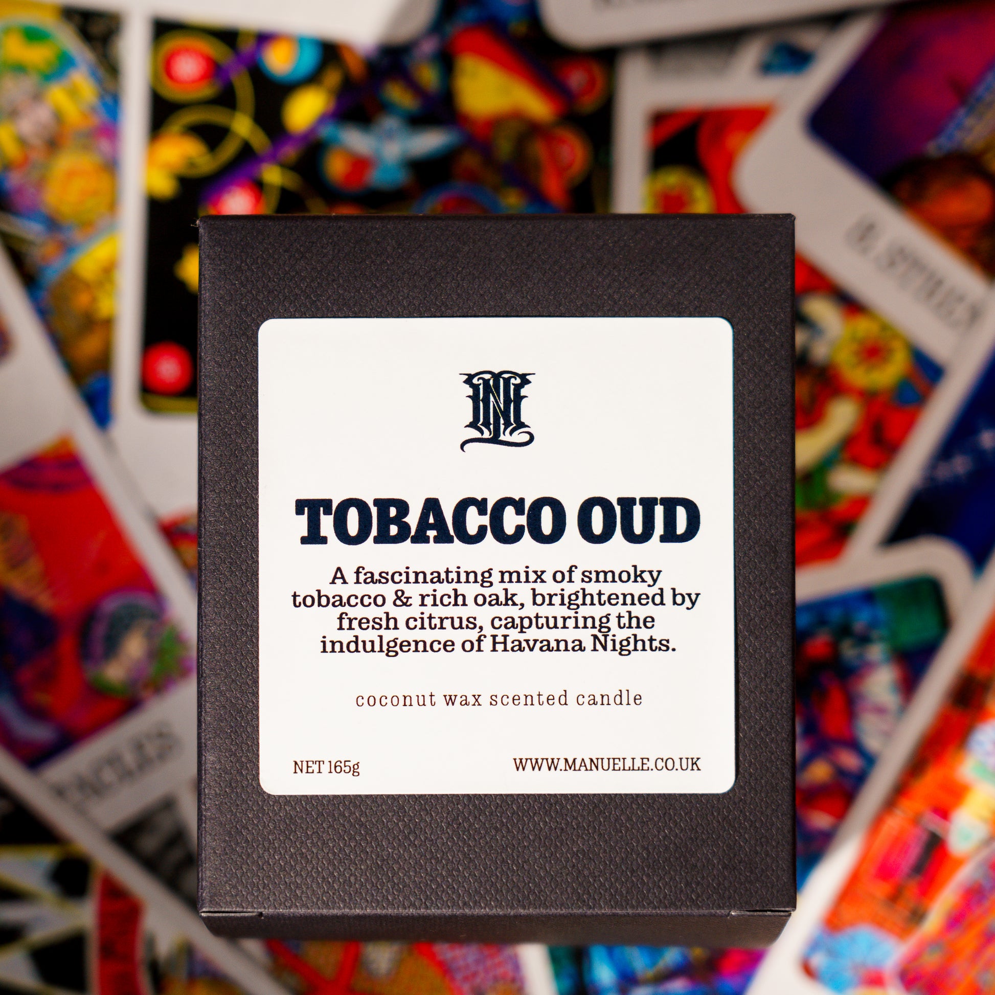 Manuelle Tobacco Oud candle packaging with colorful tarot card background