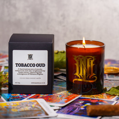 Tobacco Oud candle with packaging and tarot cards on a textured surface