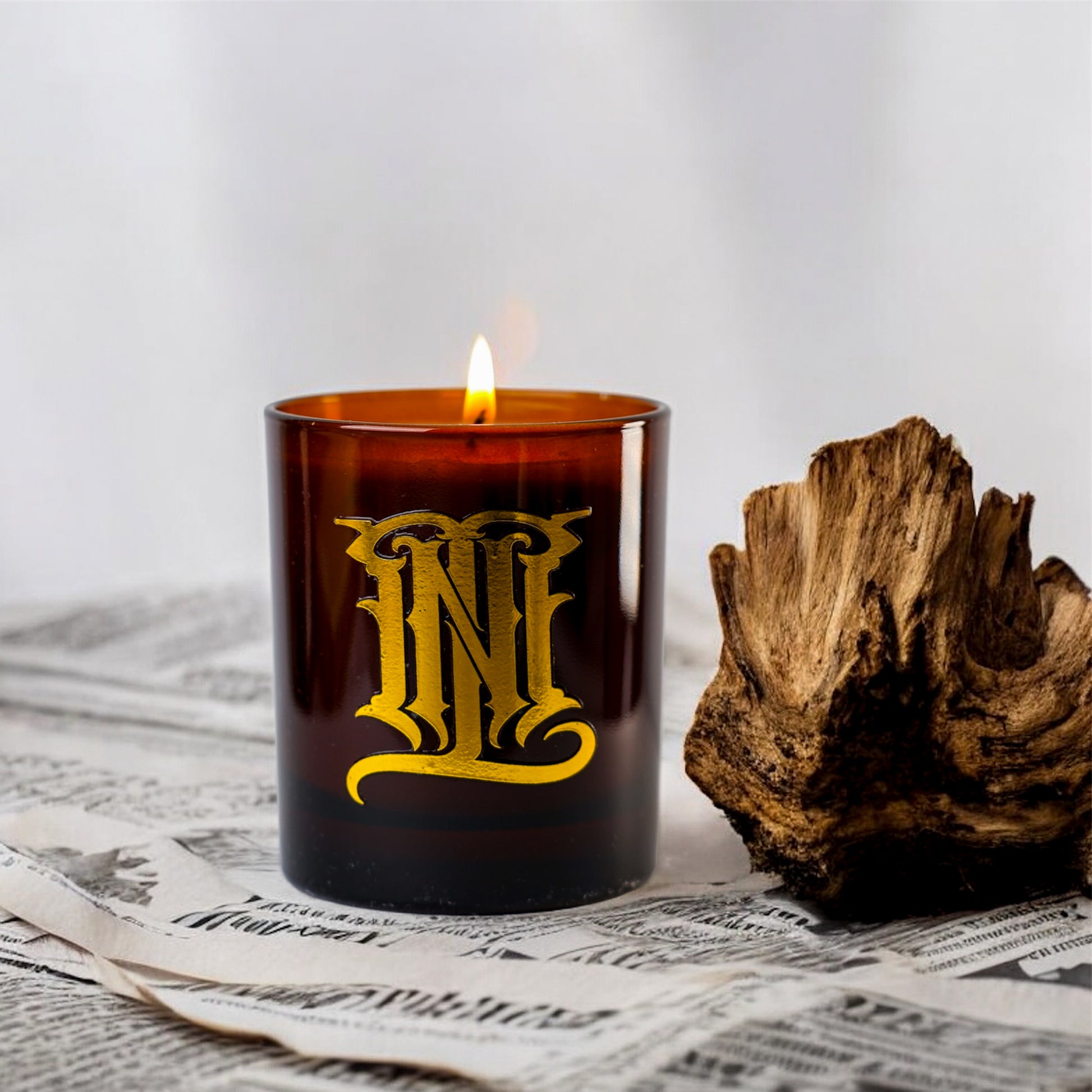 Brown candle with gold lettering on a newspaper background